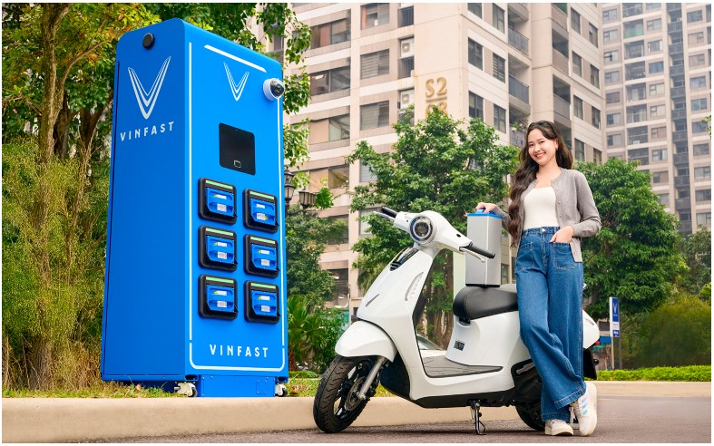 Cô gái đứng cạnh xe máy điện màu trắng bên trạm đổi pin