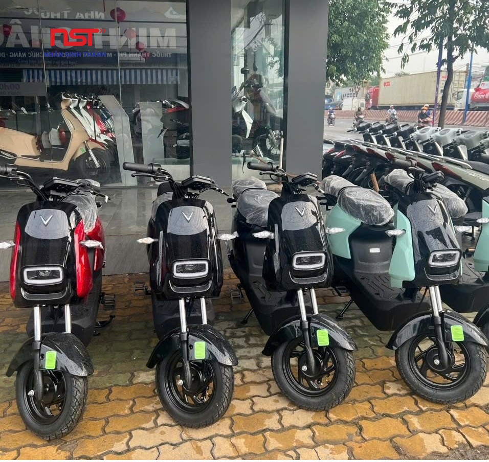 Dãy xe máy điện màu trắng và đen đỗ trên vỉa hè trước cửa hàng