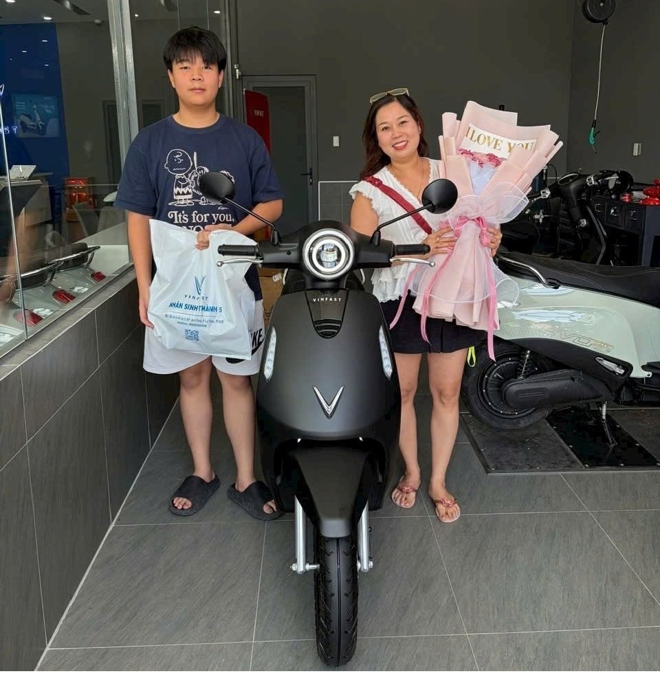 Hai mẹ con nhận xe máy điện màu hồng tại cửa hàng