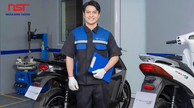 Kỹ thuật viên mặc đồng phục đứng cạnh xe máy điện trong xưởng