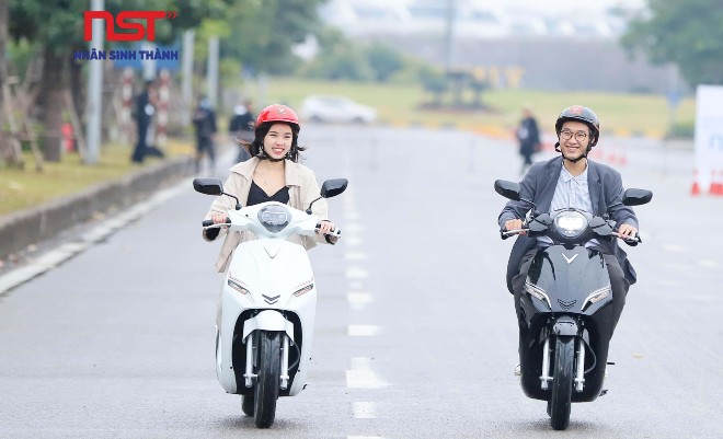 Hai người lái xe máy điện trên đường có vạch kẻ