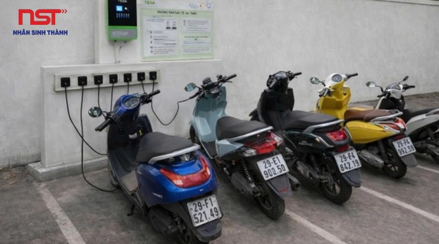 Dãy xe máy điện đỗ trước bảng ổ cắm sạc trong nhà xe