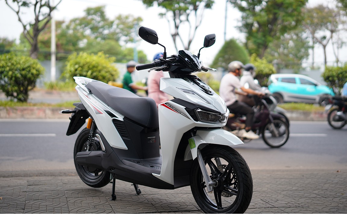 Xe máy điện VinFast Viper màu trắng chạy trên đường có cây xanh